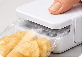 A hand pressing SnapSeal Mini onto a bag of chips